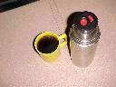 Yellow plastic mug of coffee and flask.